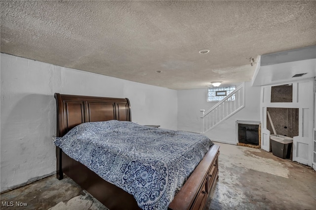 bedroom with a fireplace, concrete flooring, and a textured ceiling