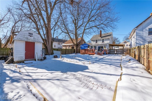 yard layered in snow with a deck and a storage unit