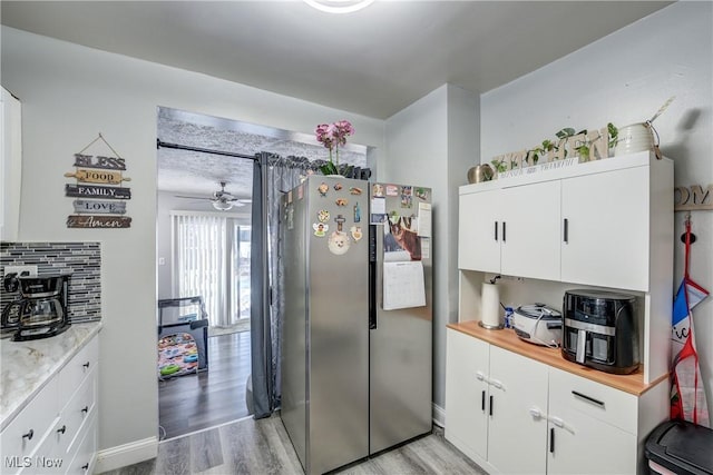 kitchen with wood counters, white cabinetry, stainless steel fridge, light hardwood / wood-style floors, and backsplash