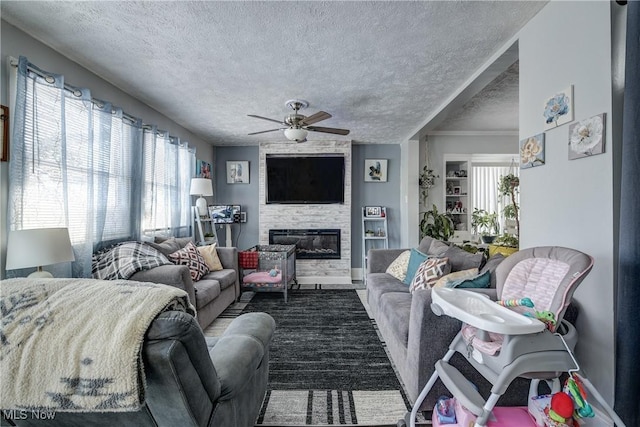 living room featuring a fireplace, a wealth of natural light, a textured ceiling, and ceiling fan