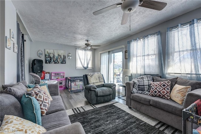 living room featuring ceiling fan, a textured ceiling, and light hardwood / wood-style floors