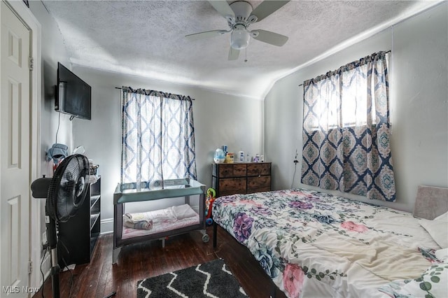 bedroom with ceiling fan, dark hardwood / wood-style floors, vaulted ceiling, and a textured ceiling