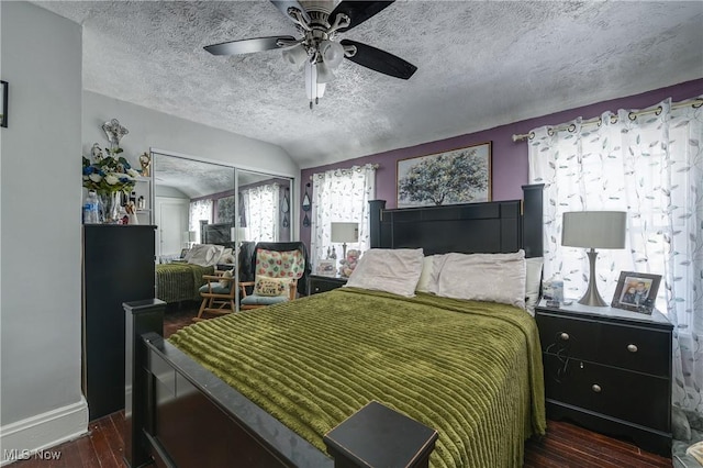 bedroom featuring vaulted ceiling, dark hardwood / wood-style flooring, ceiling fan, a textured ceiling, and a closet