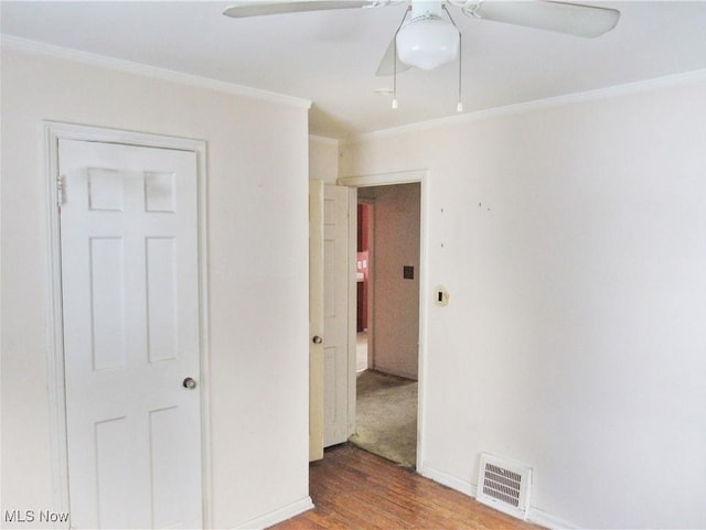 unfurnished bedroom with crown molding, wood-type flooring, ceiling fan, and a closet