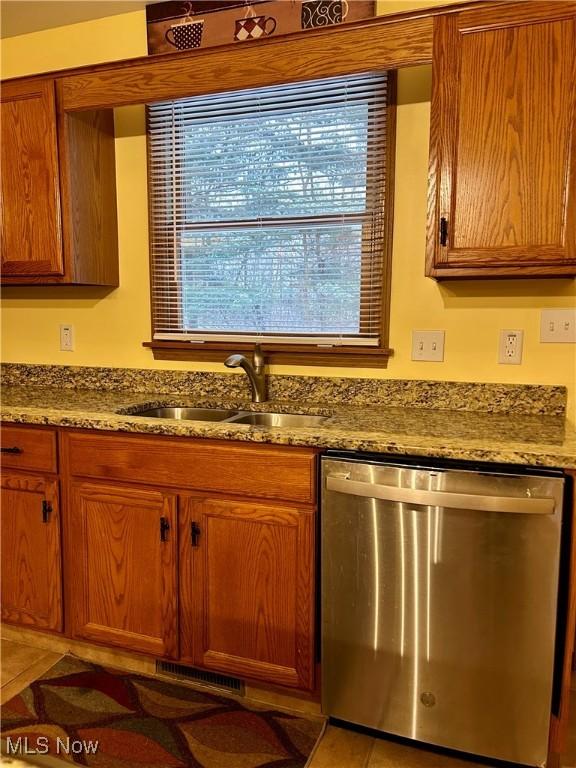 kitchen featuring sink, stainless steel dishwasher, tile patterned floors, and dark stone counters