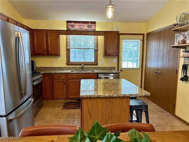 kitchen with a kitchen island, decorative light fixtures, sink, light tile patterned floors, and stainless steel appliances