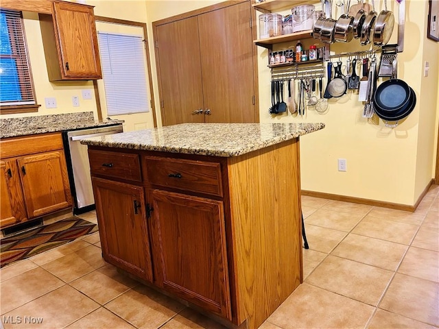 kitchen with light stone countertops, a center island, dishwasher, and light tile patterned flooring