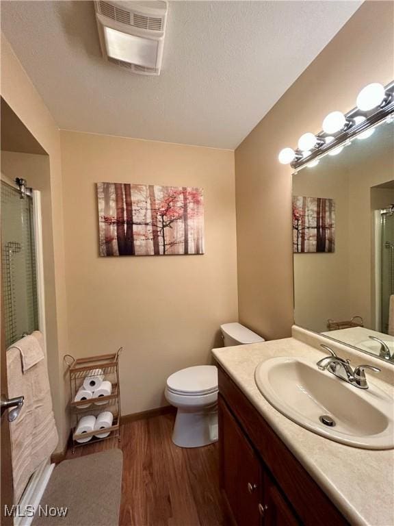 bathroom featuring toilet, vanity, a shower with door, and hardwood / wood-style floors