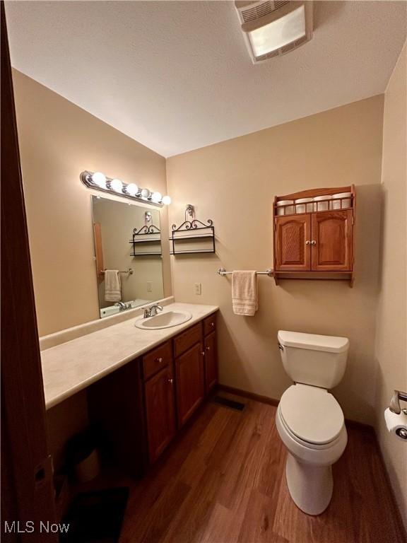 bathroom featuring wood-type flooring, vanity, and toilet