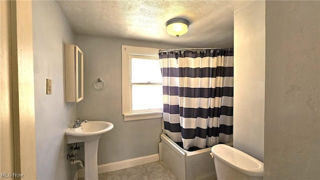 full bathroom featuring sink, shower / tub combo, tile patterned flooring, a textured ceiling, and toilet