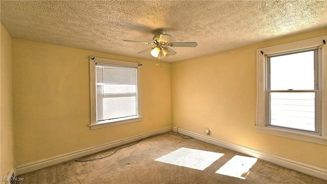 carpeted spare room featuring a textured ceiling, a wealth of natural light, and ceiling fan