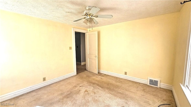 empty room with light carpet, ceiling fan, and a textured ceiling