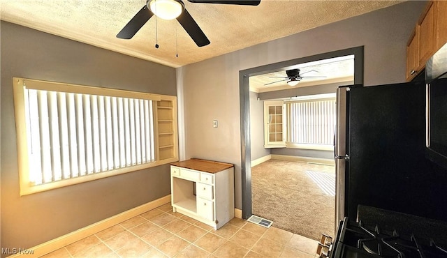 interior space featuring stainless steel refrigerator, light colored carpet, ceiling fan, and a textured ceiling