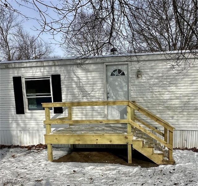 snow covered property entrance featuring a wooden deck