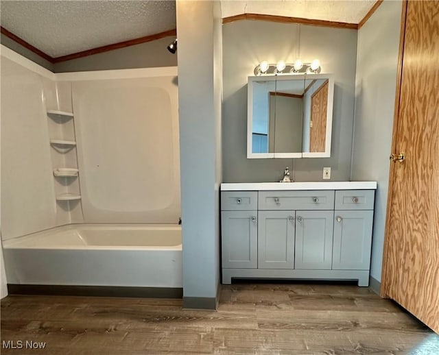 bathroom featuring vaulted ceiling, shower / bathtub combination, hardwood / wood-style flooring, vanity, and a textured ceiling