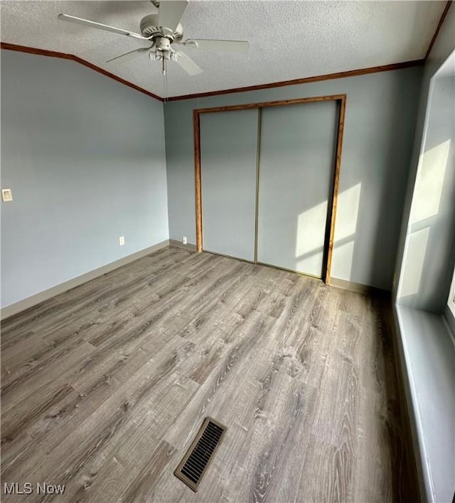 unfurnished bedroom with ceiling fan, hardwood / wood-style floors, a closet, and a textured ceiling