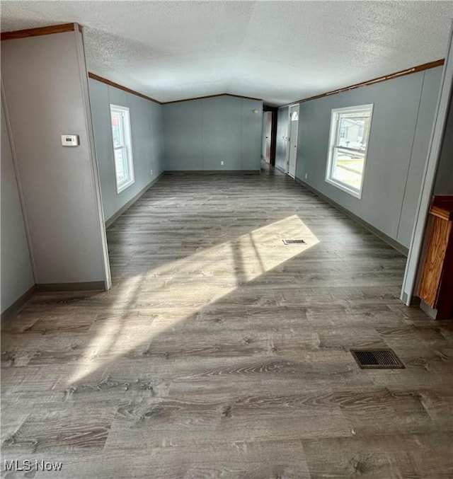 unfurnished room with lofted ceiling, hardwood / wood-style floors, plenty of natural light, and ornamental molding