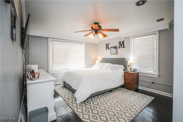 bedroom featuring multiple windows, dark hardwood / wood-style floors, and ceiling fan