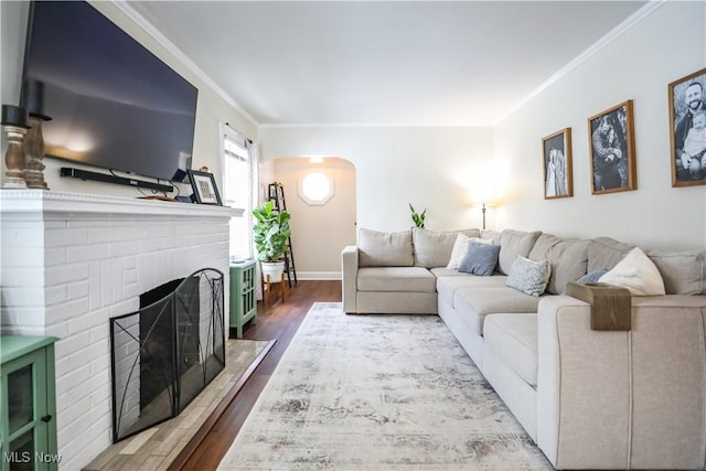 living room with a brick fireplace, ornamental molding, and hardwood / wood-style floors