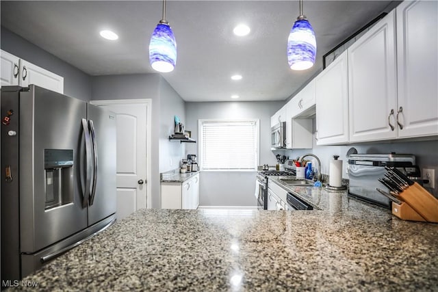 kitchen with stainless steel appliances, white cabinetry, and hanging light fixtures