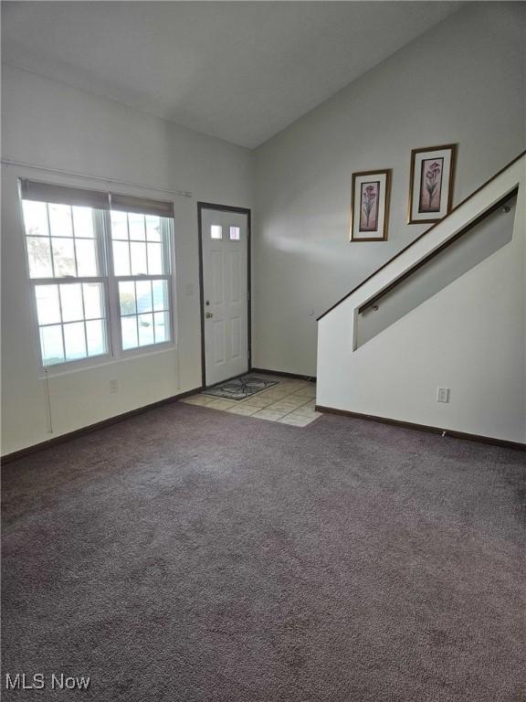 entryway with lofted ceiling and light colored carpet