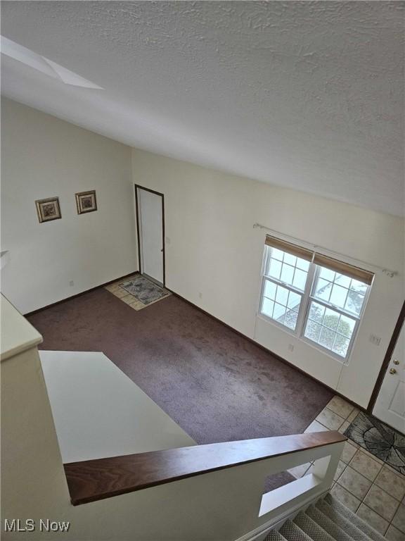 entryway with lofted ceiling, tile patterned floors, and a textured ceiling