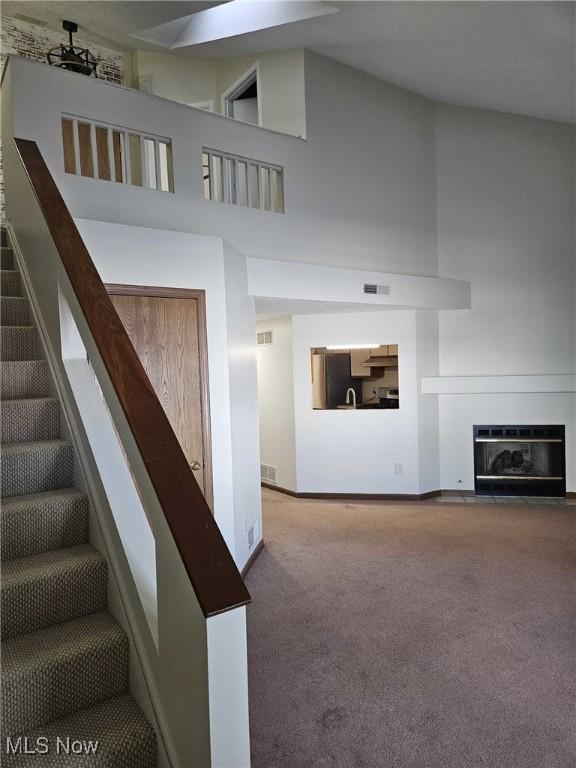 stairway with a towering ceiling and carpet flooring