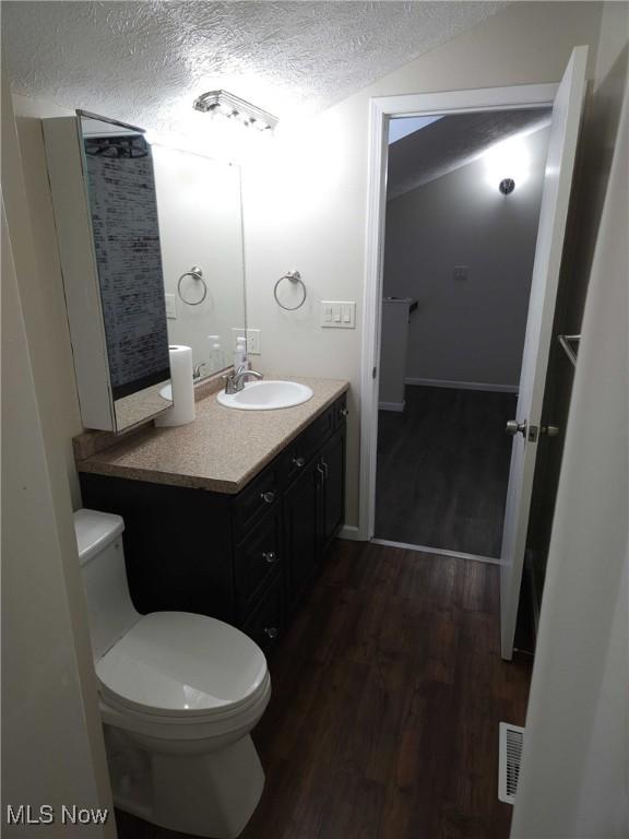 bathroom featuring hardwood / wood-style flooring, vanity, a textured ceiling, and toilet