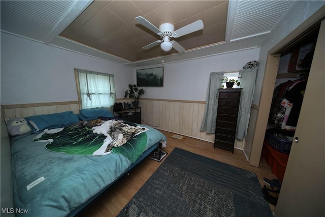 bedroom featuring hardwood / wood-style flooring, a tray ceiling, ceiling fan, and a closet