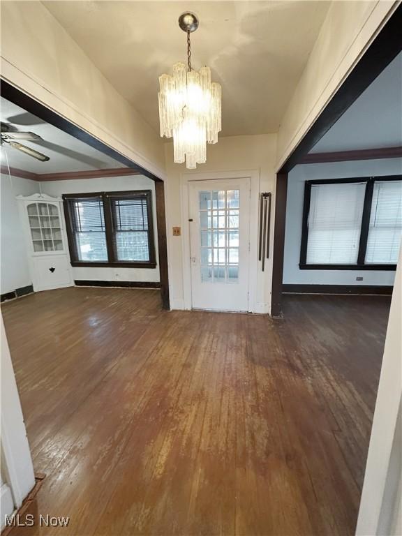 interior space with crown molding, ceiling fan with notable chandelier, and dark hardwood / wood-style floors