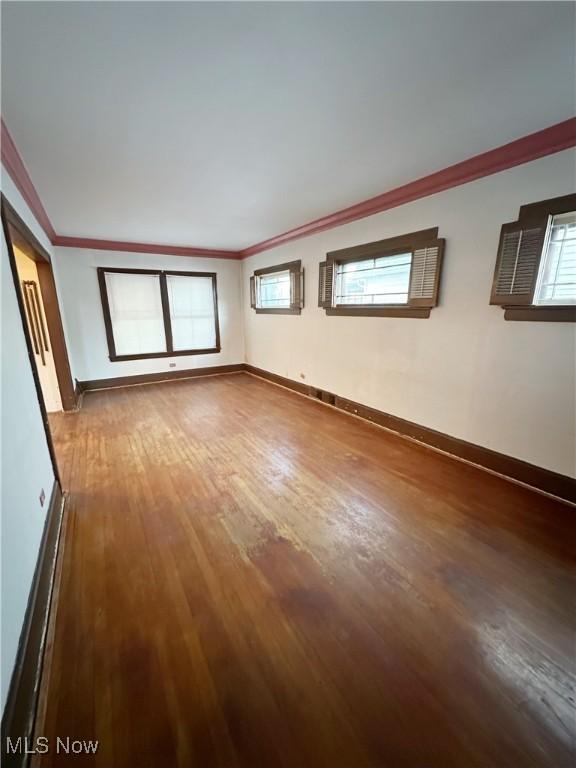 empty room with crown molding and wood-type flooring