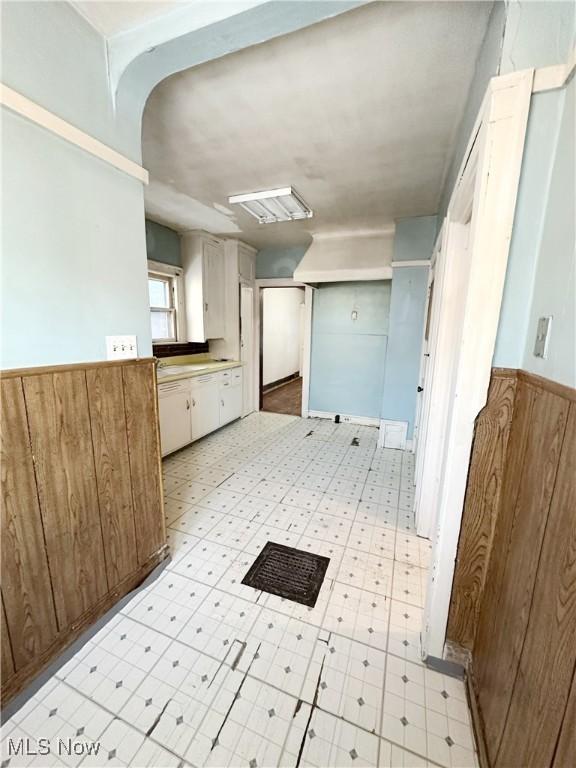 kitchen featuring white cabinets and wood walls