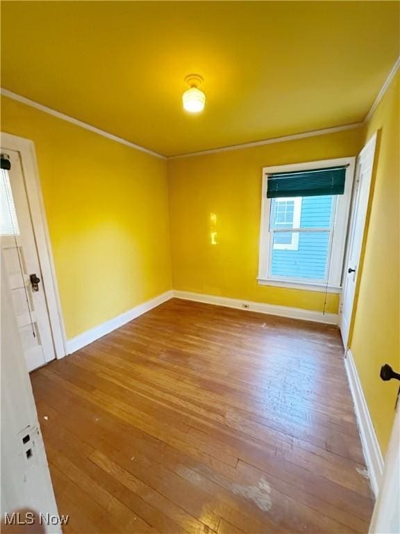 empty room with ornamental molding and hardwood / wood-style floors