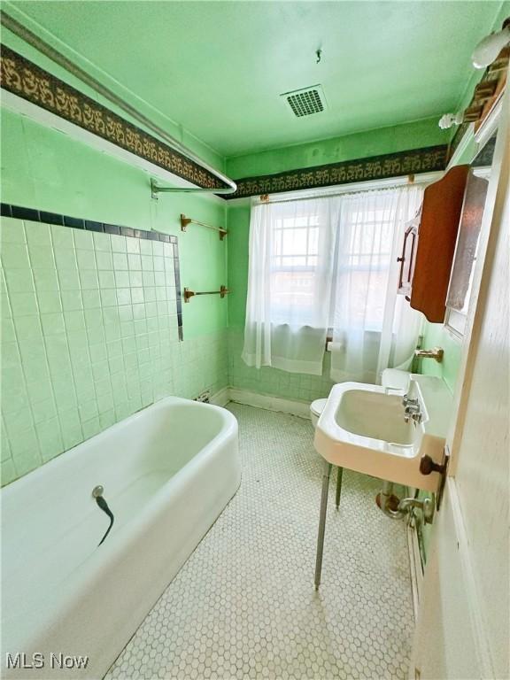 full bathroom with tile walls, sink, toilet, and shower / bath combination