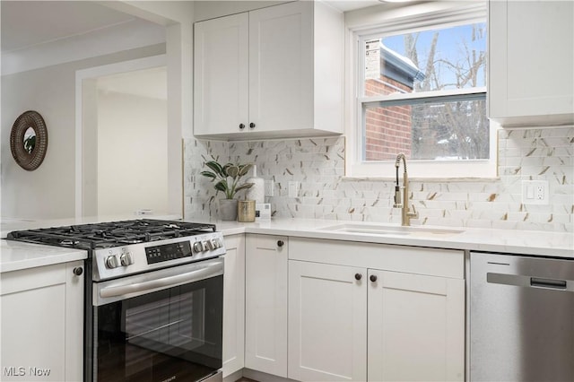 kitchen with white cabinetry, stainless steel appliances, sink, and tasteful backsplash