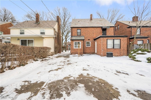 snow covered back of property featuring central AC