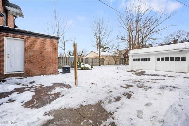 snowy yard featuring a garage, an outdoor structure, and central air condition unit