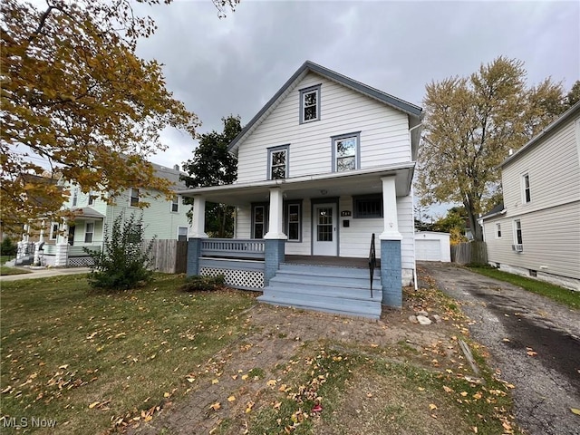 view of front of property featuring a garage, an outbuilding, covered porch, and a front lawn