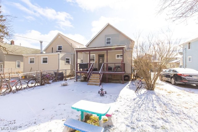 snow covered rear of property with covered porch