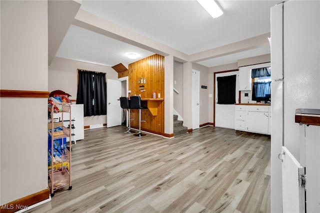 living room with baseboards, light wood finished floors, stairway, and indoor bar