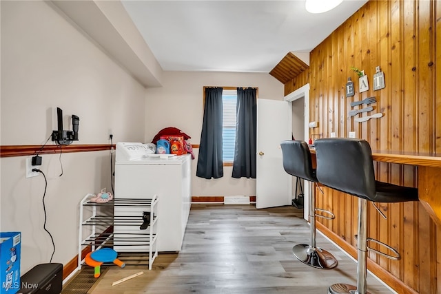 interior space featuring wood walls, wood finished floors, washer / dryer, and baseboards