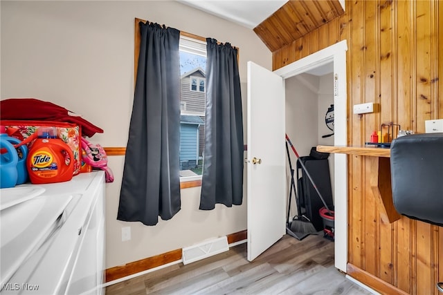bedroom featuring wooden walls, wood finished floors, visible vents, and baseboards