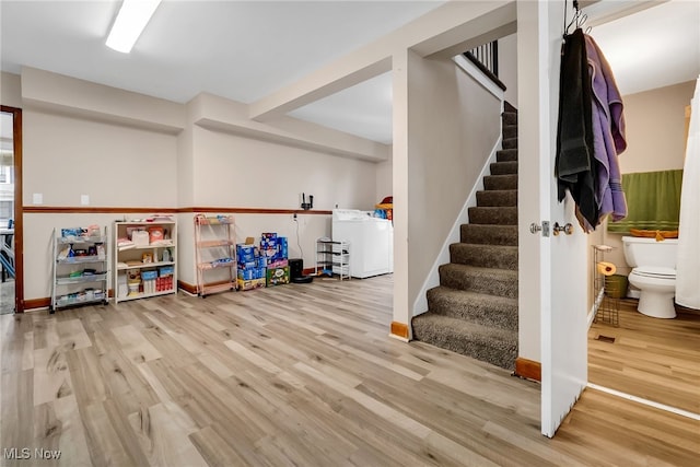 rec room with wood finished floors, washer / dryer, and baseboards