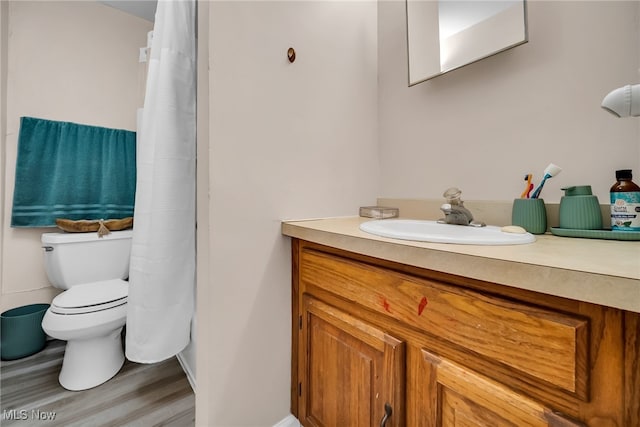 full bath with wood finished floors, a shower with shower curtain, toilet, vanity, and baseboards