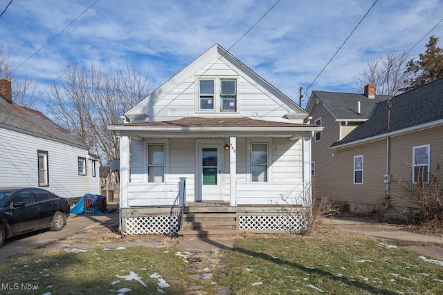 bungalow with covered porch and a front lawn