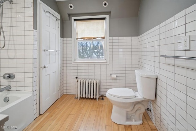 bathroom with shower / bathtub combination, toilet, radiator, and tile walls