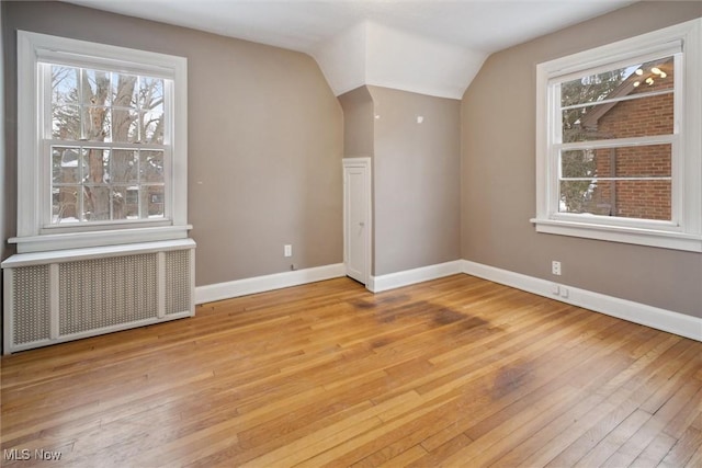 interior space featuring lofted ceiling, radiator heating unit, and light hardwood / wood-style floors