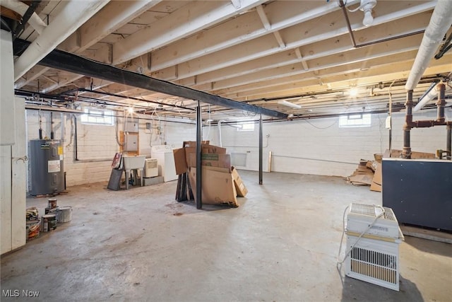 basement with water heater, washing machine and dryer, and sink