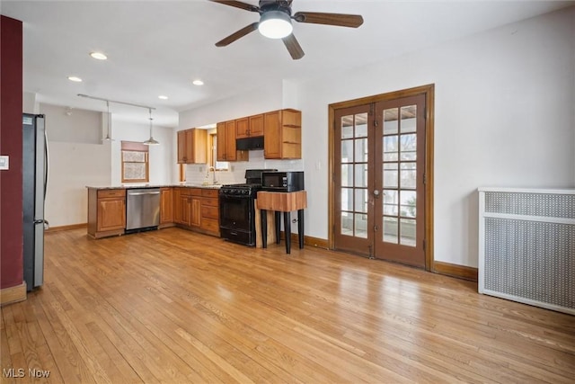 kitchen featuring sink, radiator heating unit, black appliances, decorative light fixtures, and french doors