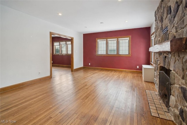 unfurnished living room featuring a stone fireplace and light wood-type flooring